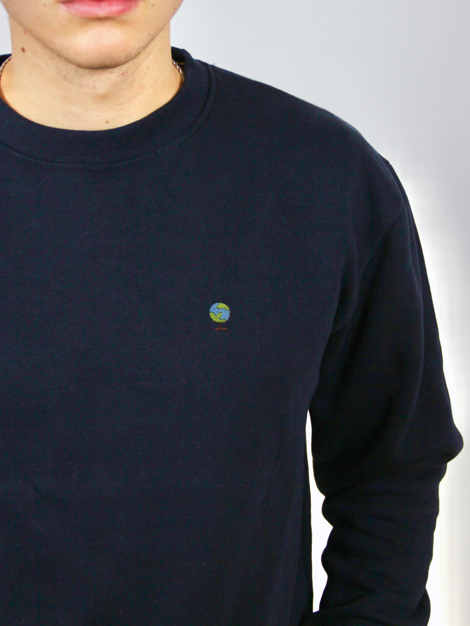 Globus-Stickerei auf dem dunkelblauen Sweater, Nahaufnahme