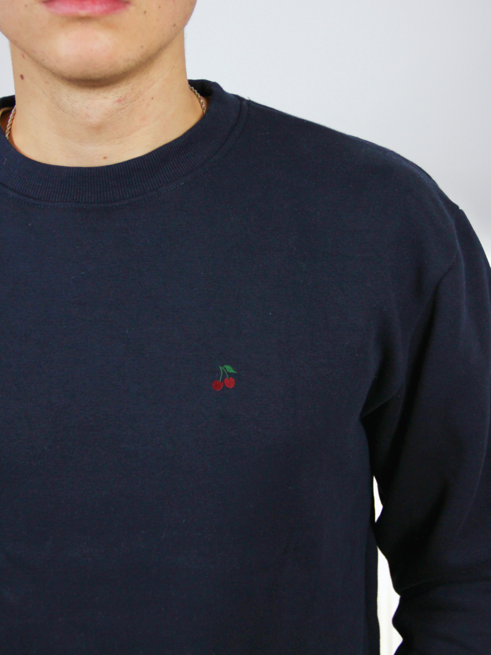 Kirschen-Stickerei auf dem dunkelblauen Sweater, Nahaufnahme