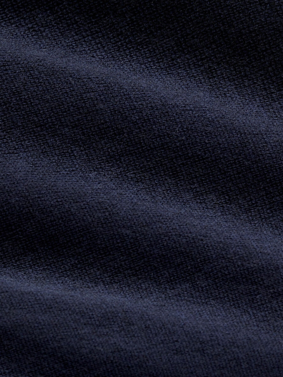 Nahaufnahme der Feinstrick-Struktur auf dem dunkelblauen Poloshirt, Nahaufnahme