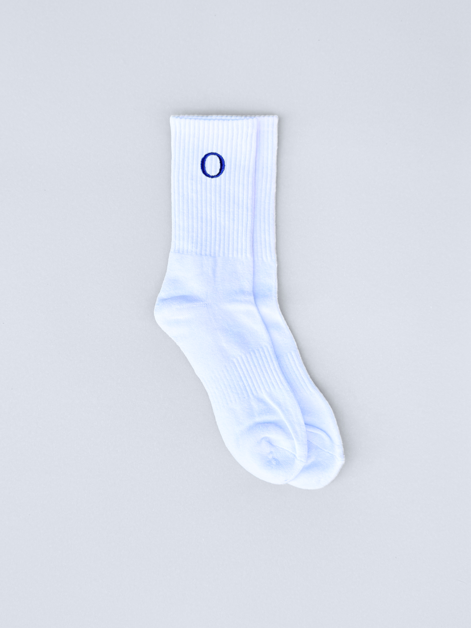 Weiße Socken mit gestickter Initiale O, flach ausgebreitet