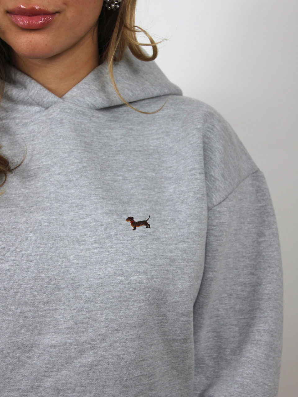 Dackel-Stickerei auf dem hellgrauen Hoodie, Nahaufnahme