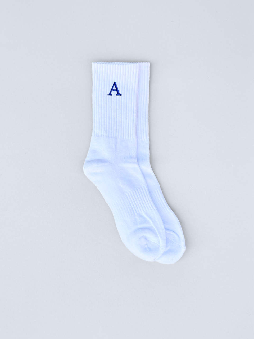 Weiße Socken mit gestickter Initiale A, flach ausgebreitet