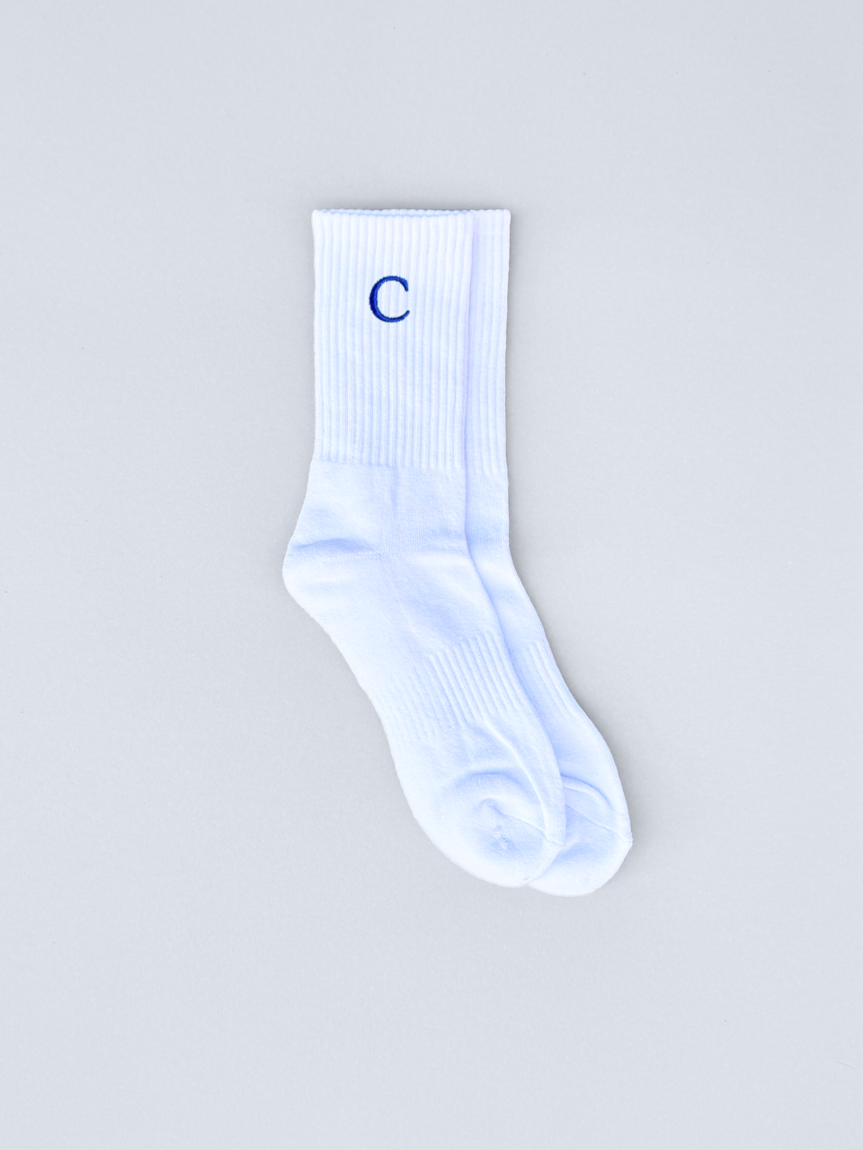 Weiße Socken mit gestickter Initiale C, flach ausgebreitet