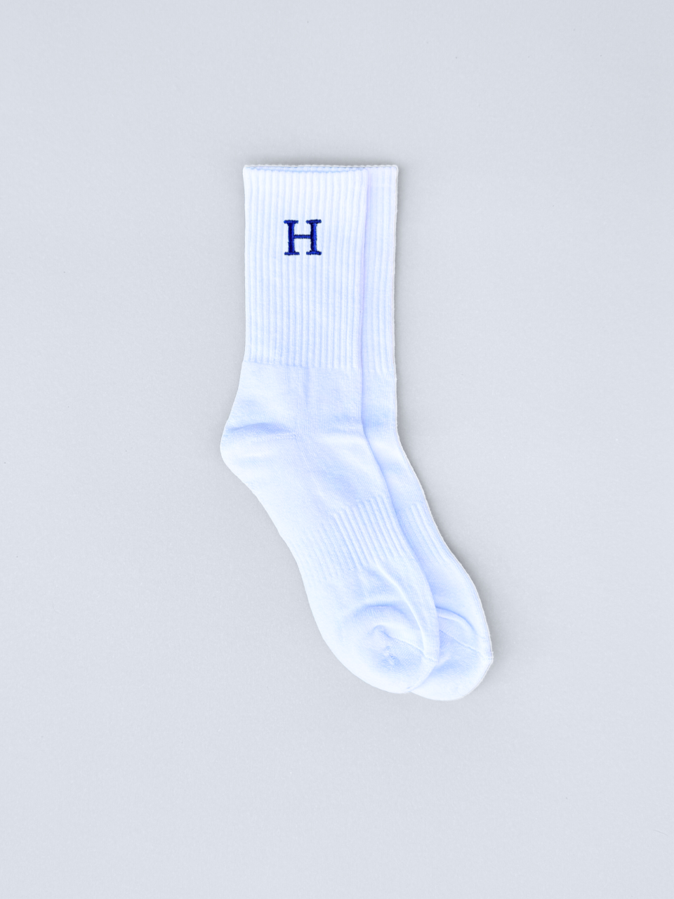 Weiße Socken mit gestickter Initiale H, flach ausgebreitet