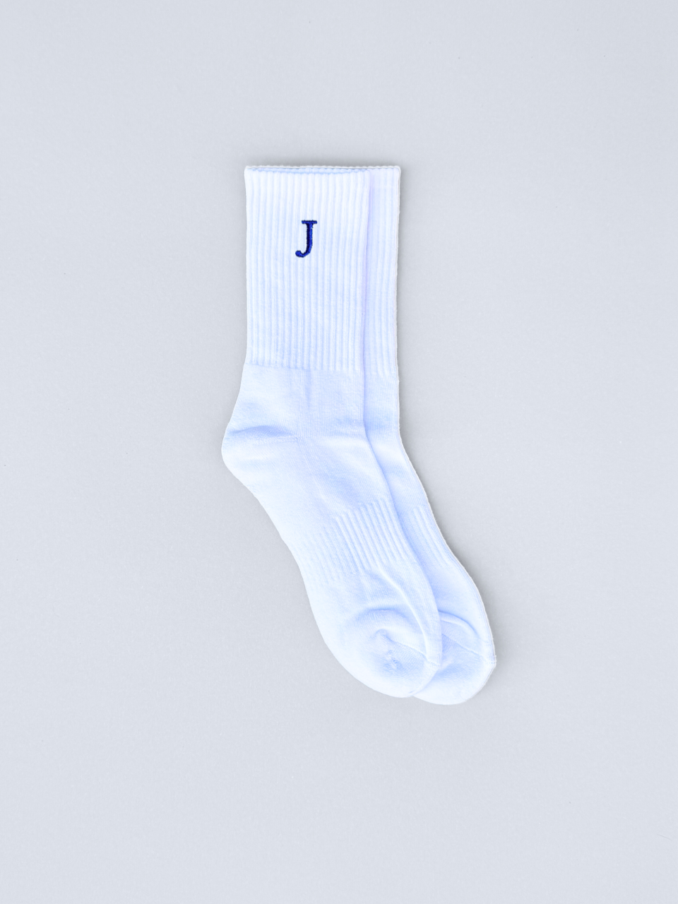 Weiße Socken mit gestickter Initiale J, flach ausgebreitet
