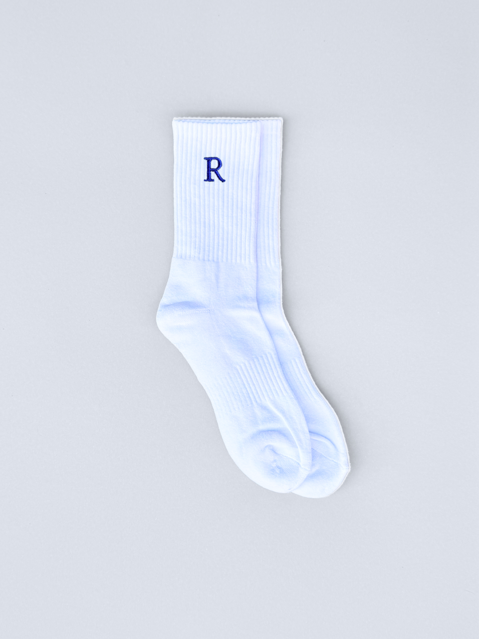 Weiße Socken mit gestickter Initiale R, flach ausgebreitet