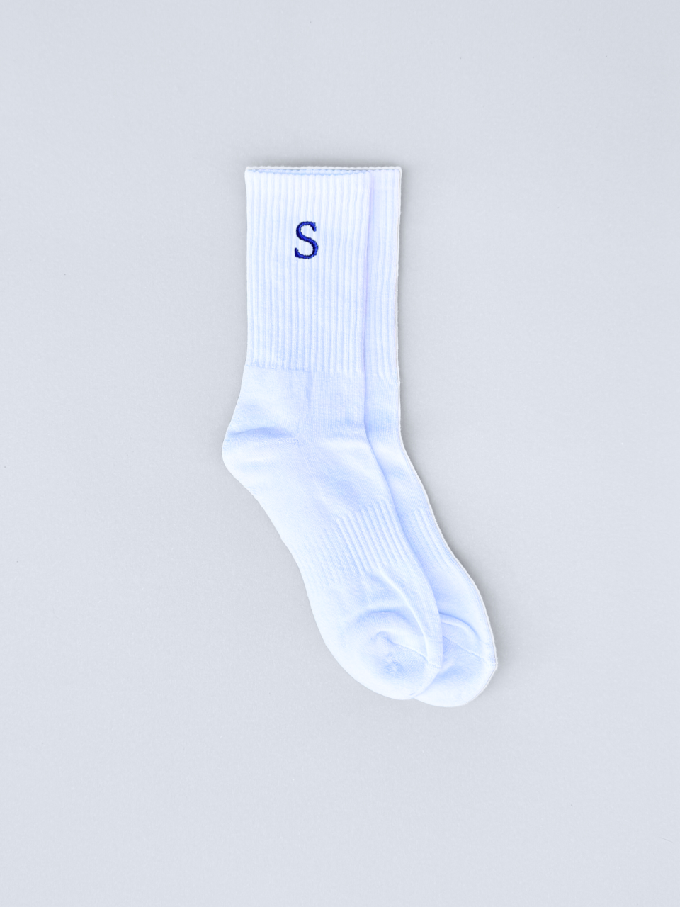 Weiße Socken mit gestickter Initiale S, flach ausgebreitet