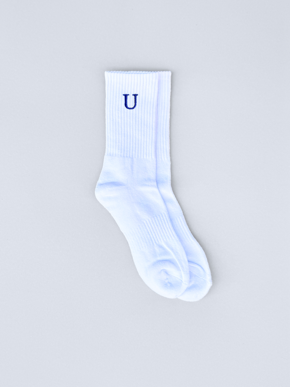 Weiße Socken mit gestickter Initiale U, flach ausgebreitet