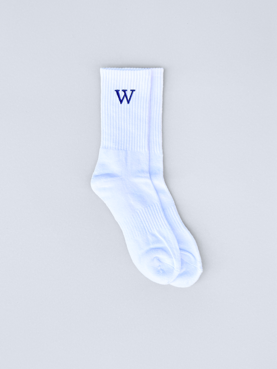 Weiße Socken mit gestickter Initiale W, flach ausgebreitet