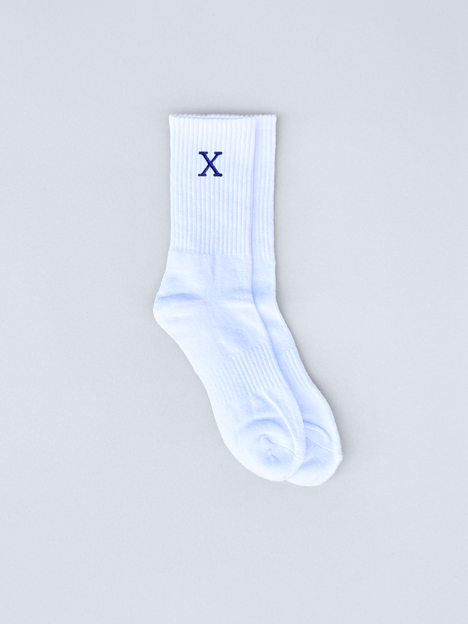 Weiße Socken mit gestickter Initiale X, flach ausgebreitet